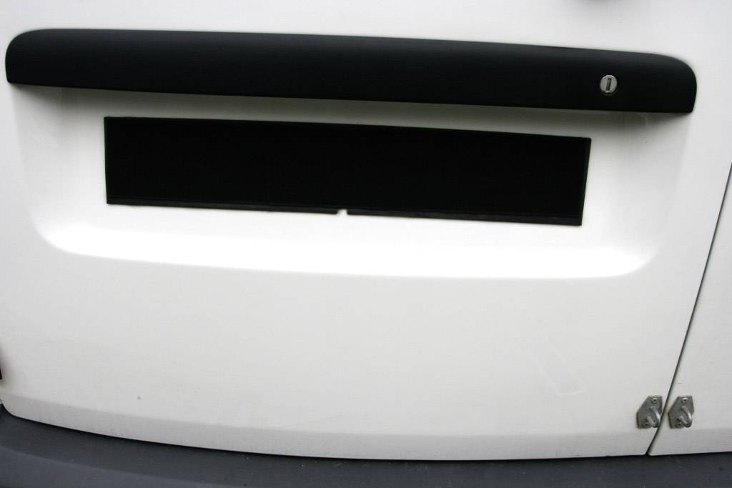 Bijela ploha s crnim, pravokutnim otvorom i crnom trakom iznad njega.