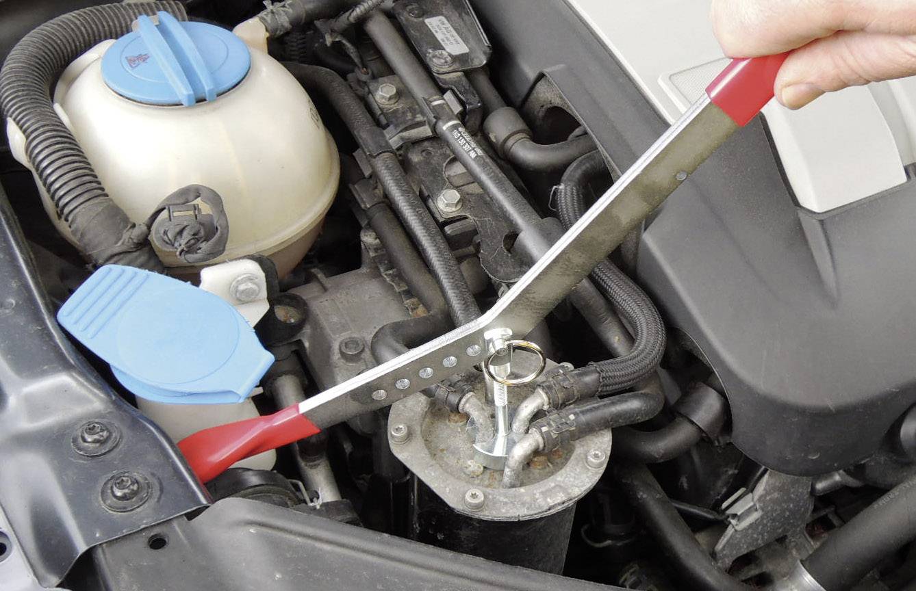 Jedna osoba koristi odzračni ključ za otvaranje separatora ulja u motornom prostoru automobila.