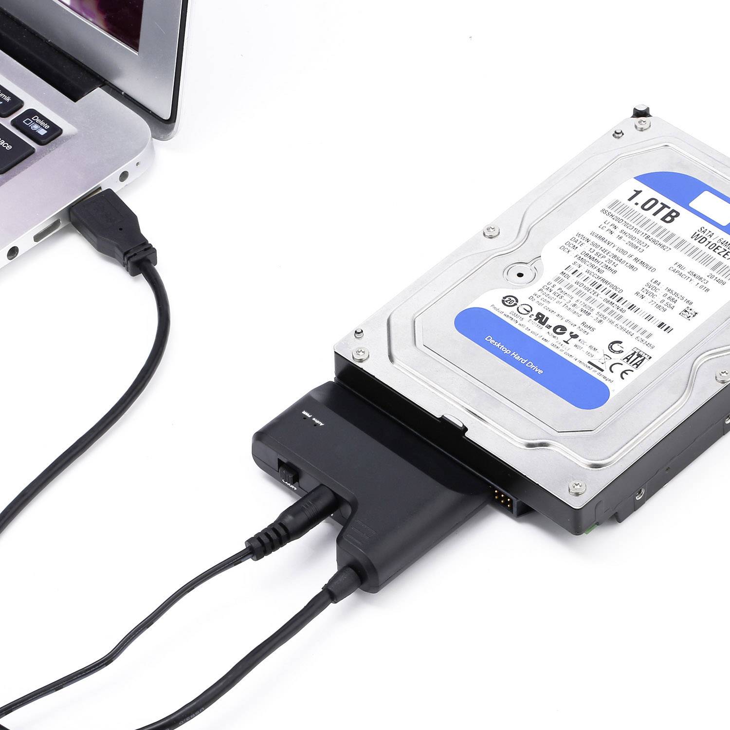Vanjski tvrdi disk s USB adapterom, spojen s prijenosnim računalom. Tvrdi disk ima kapacitet od 1 TB.