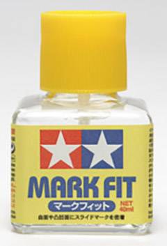 Mala plastična bočica sa žutim vijčanim čepom, natpis 'MARK FIT'. Sadrži tekućinu za lakše nanošenje modela naljepnica.