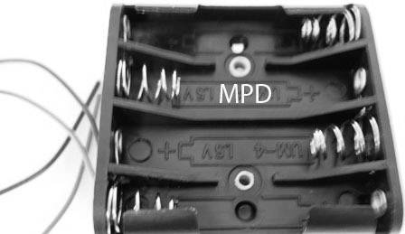 Crni nosač baterija s osam opruga za smještaj baterija, označen natpisom 'MPD' u sredini.