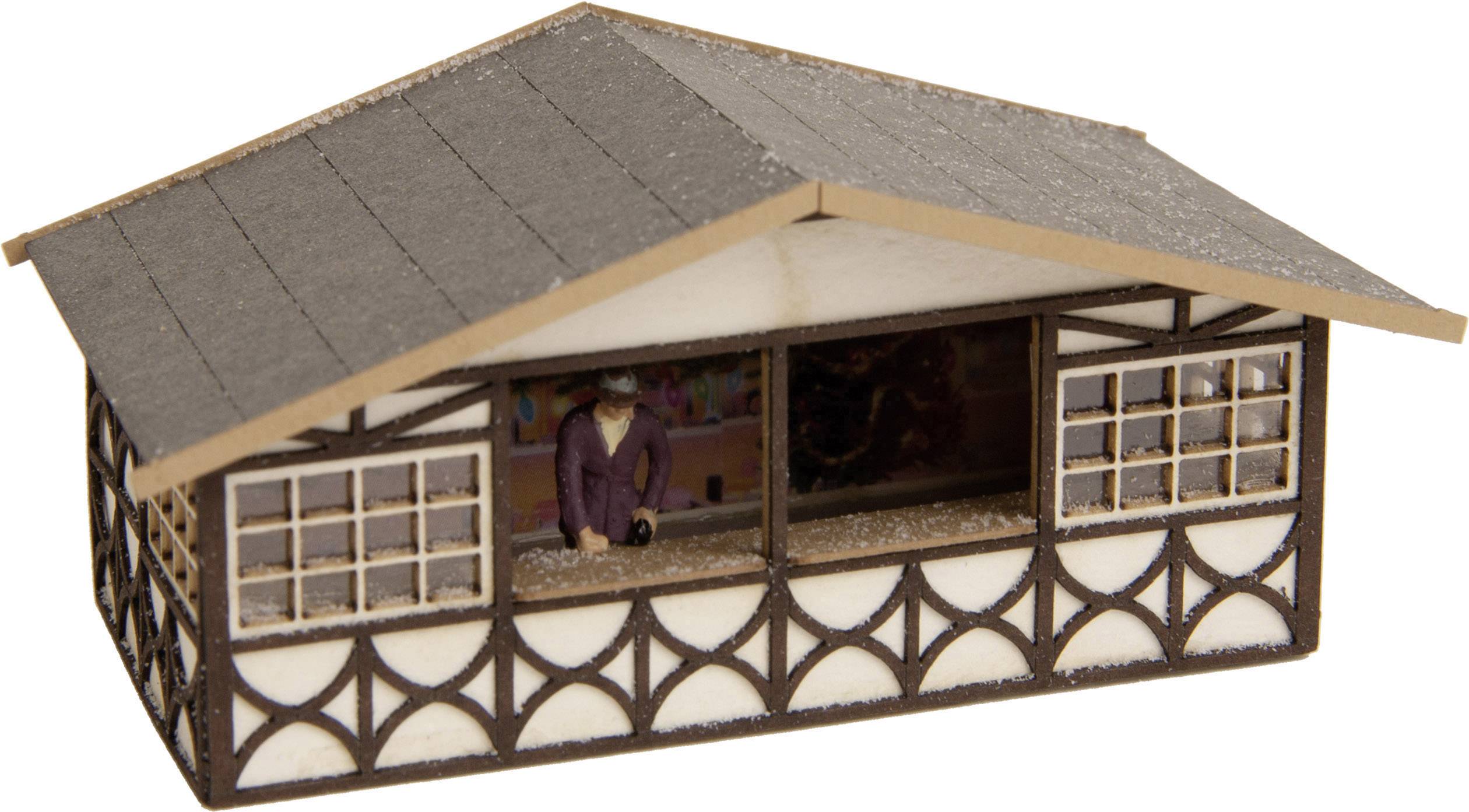Miniaturna zgrada s tradicionalnim uzorcima; mali čovjek u ljubičastoj jakni stoji naprijed s ispruženom rukom.