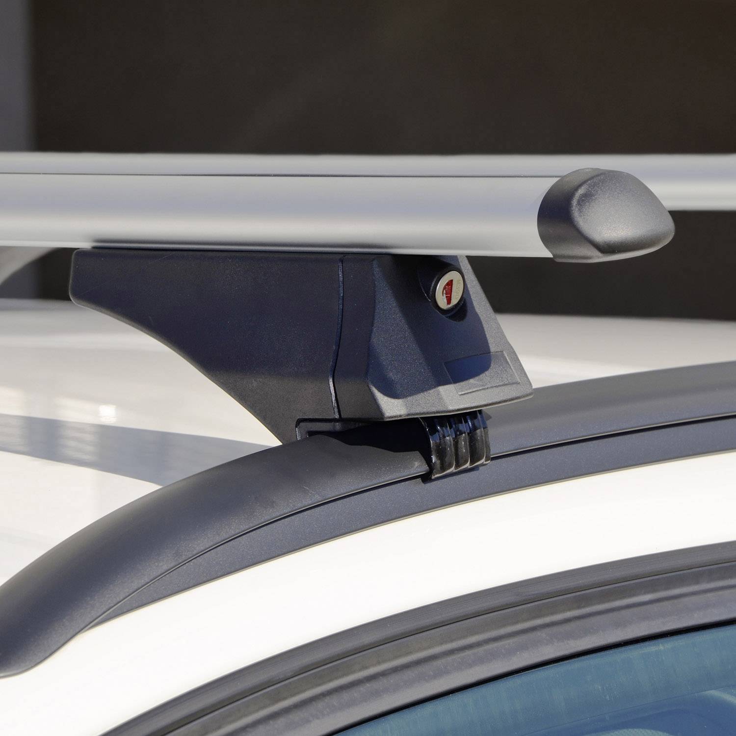 Bliski kadar nosača prtljage na bijelom automobilu. Nosač ima metalnu šipku i držač.