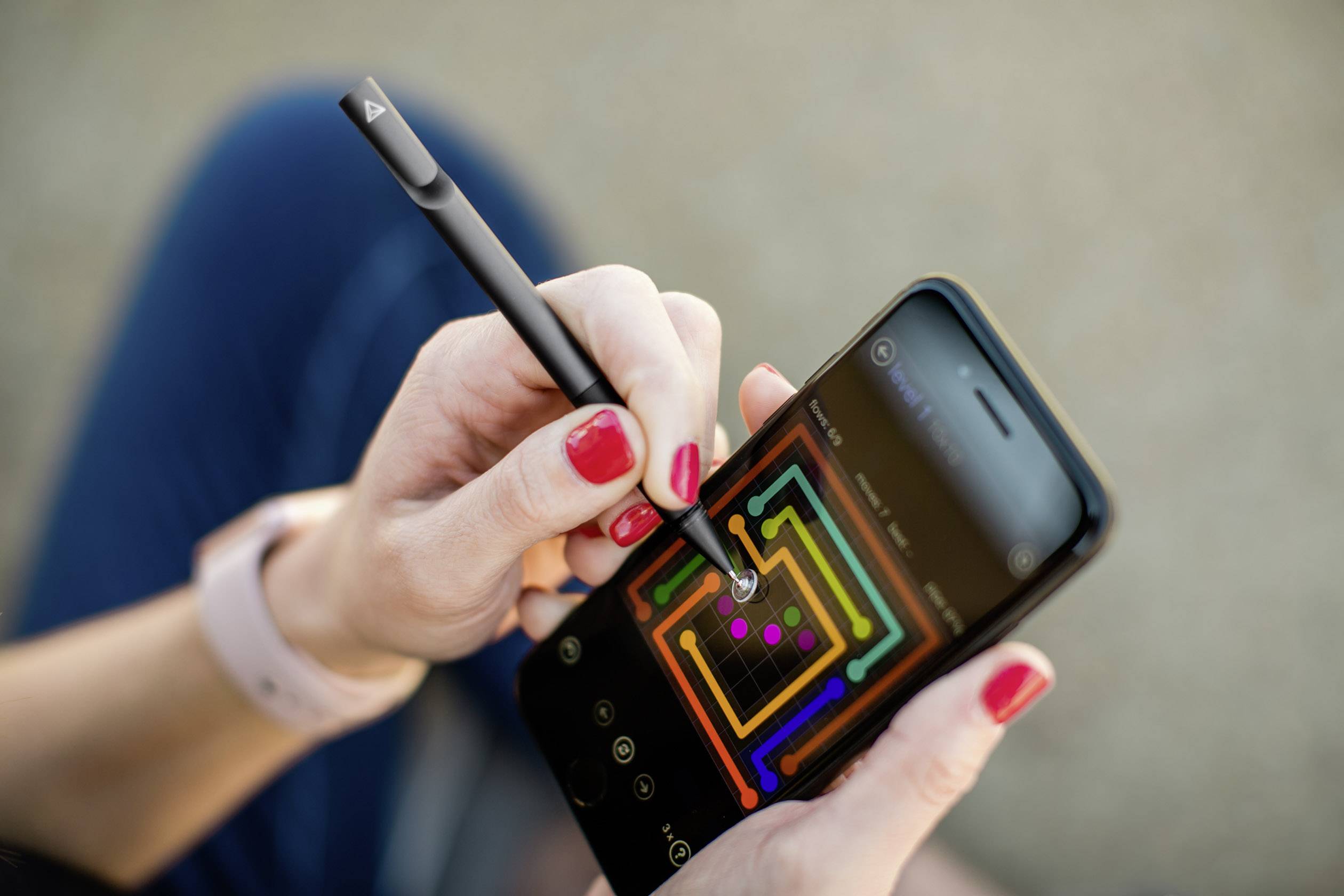 Jedna osoba koristi pametni telefon olovkom, prikazujući labirintski grafički dizajn na ekranu.