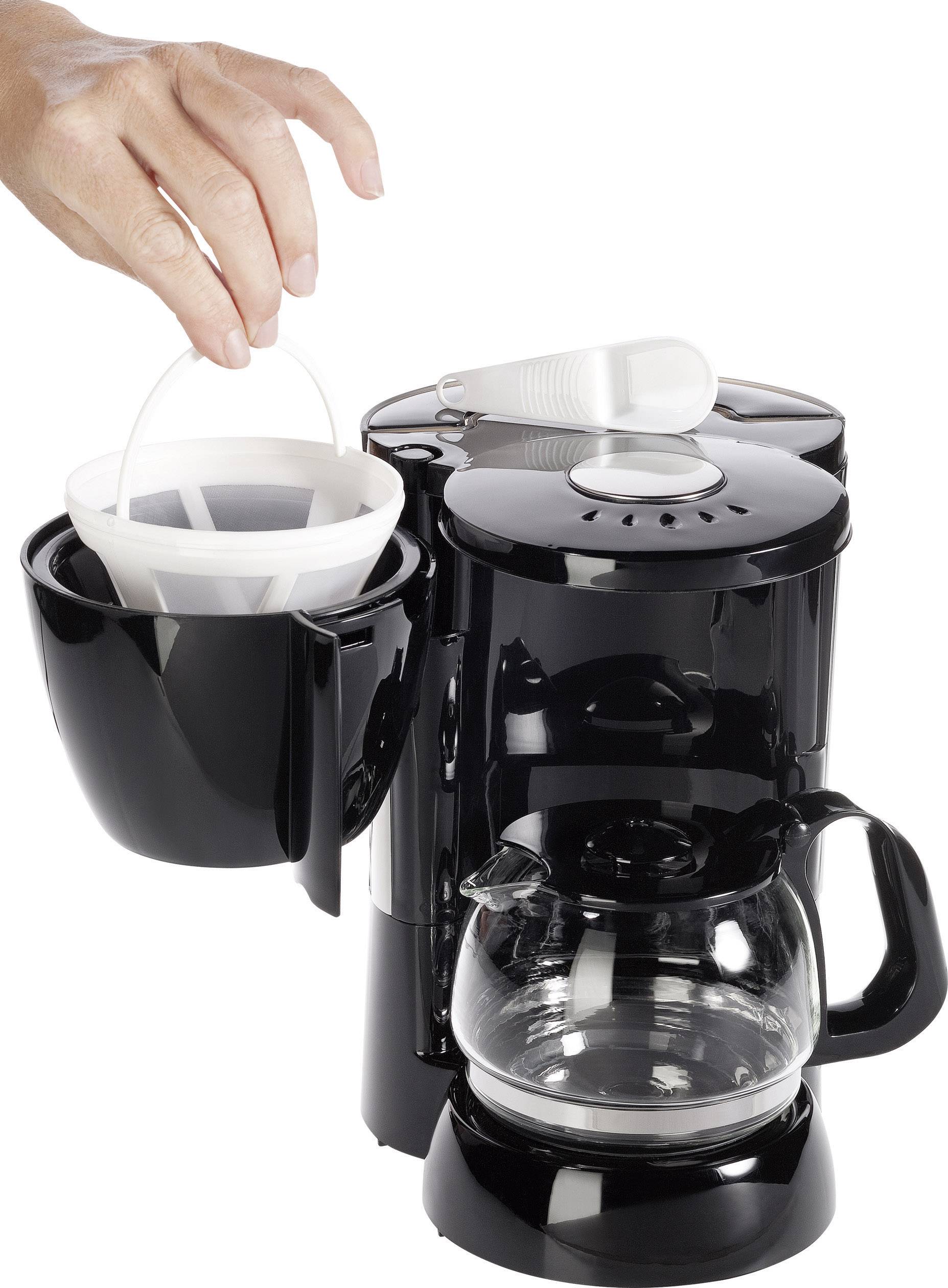 Jedna ruka diže filter za kavu iz crnog aparata za kavu sa staklenom kanistrom. Aparat se nalazi na bijeloj površini.