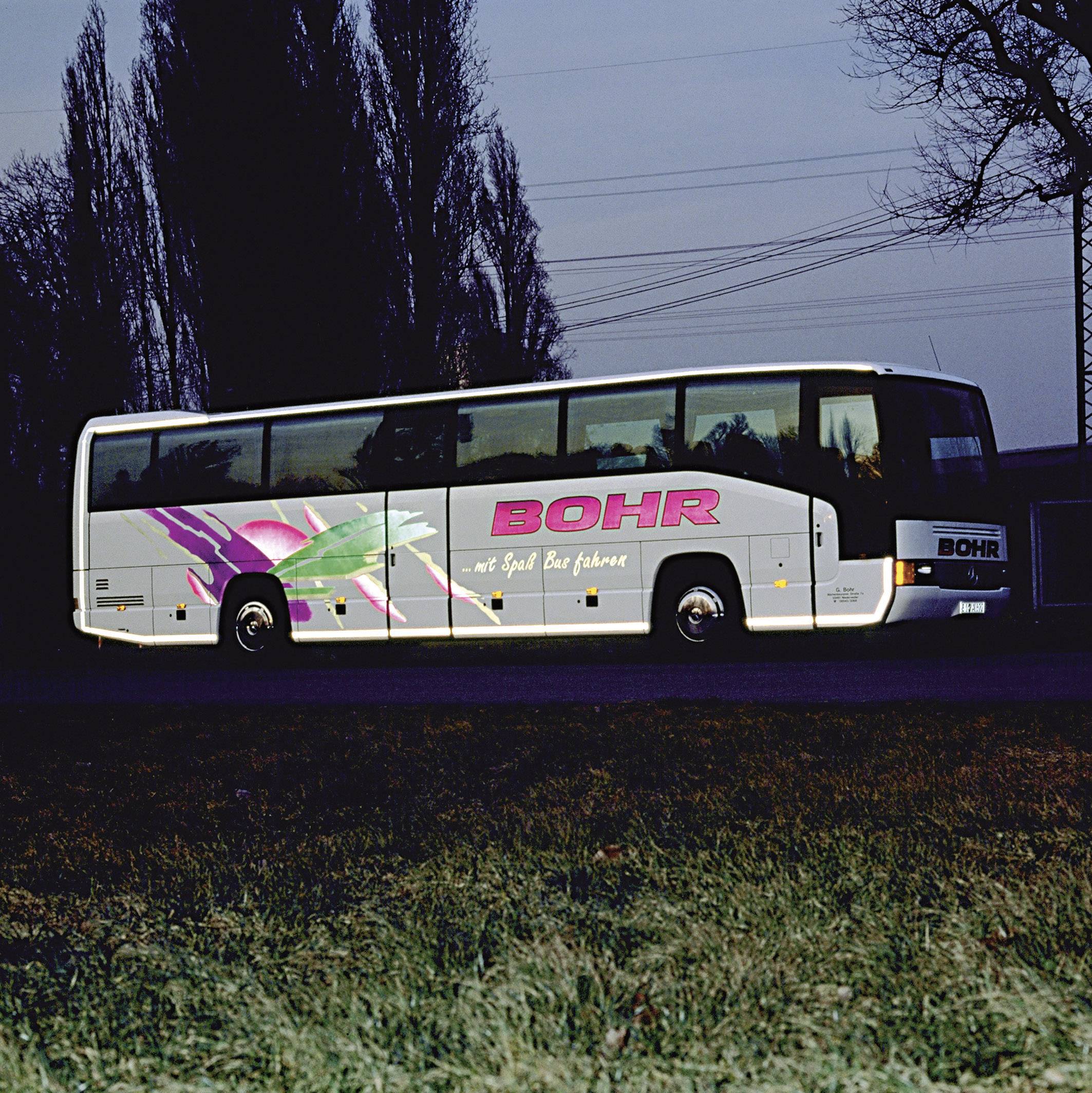 Autobus s natpisom 'BOHR' vozi cestom okruženom drvećem i električnim vodovima u sumrak.