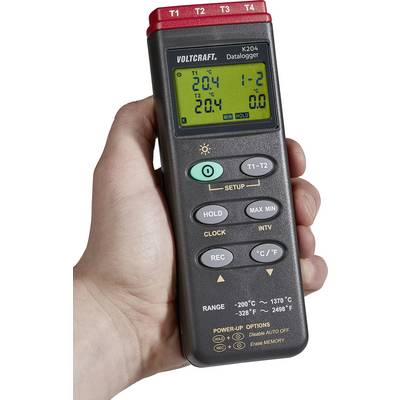 Egy kéz digitális multiméterét tartja, amelynek több gombja és kijelzője van, és Celsius-fokokban mutatja a hőmérsékleti méréseket, a 'Voltcraft' márkanévvel.