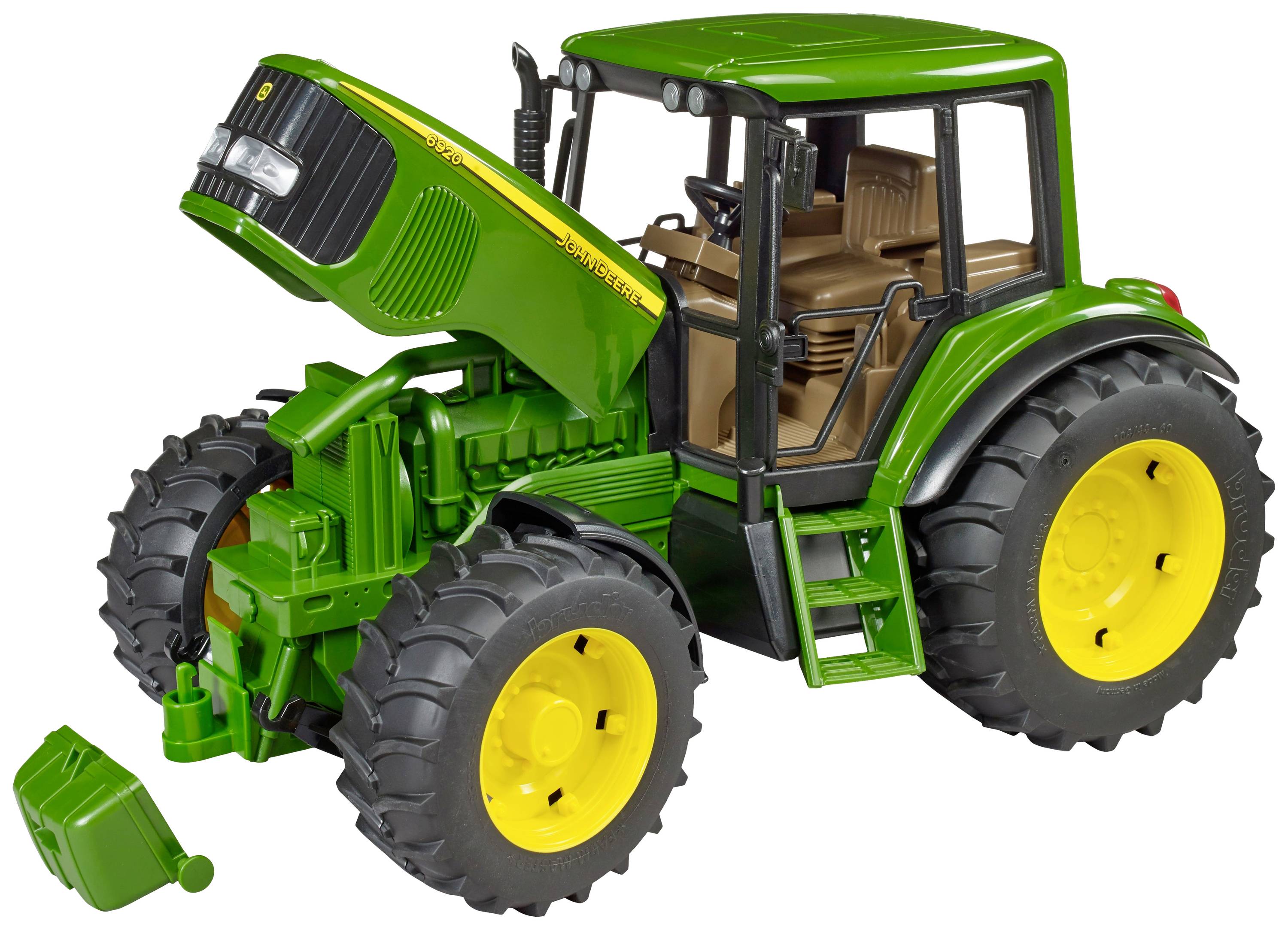 Egy zöld játék traktor sárga kerekekkel nyitott motorházzal áll. Egy levehető kanna fekszik mellette a padlón.