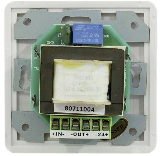 Egy elektromos áramköri modul egy kék relével felül, egy nagy tekerccsel középen és csatlakozókkal a +BE, -KI, +24V jelölésű pontoknál.