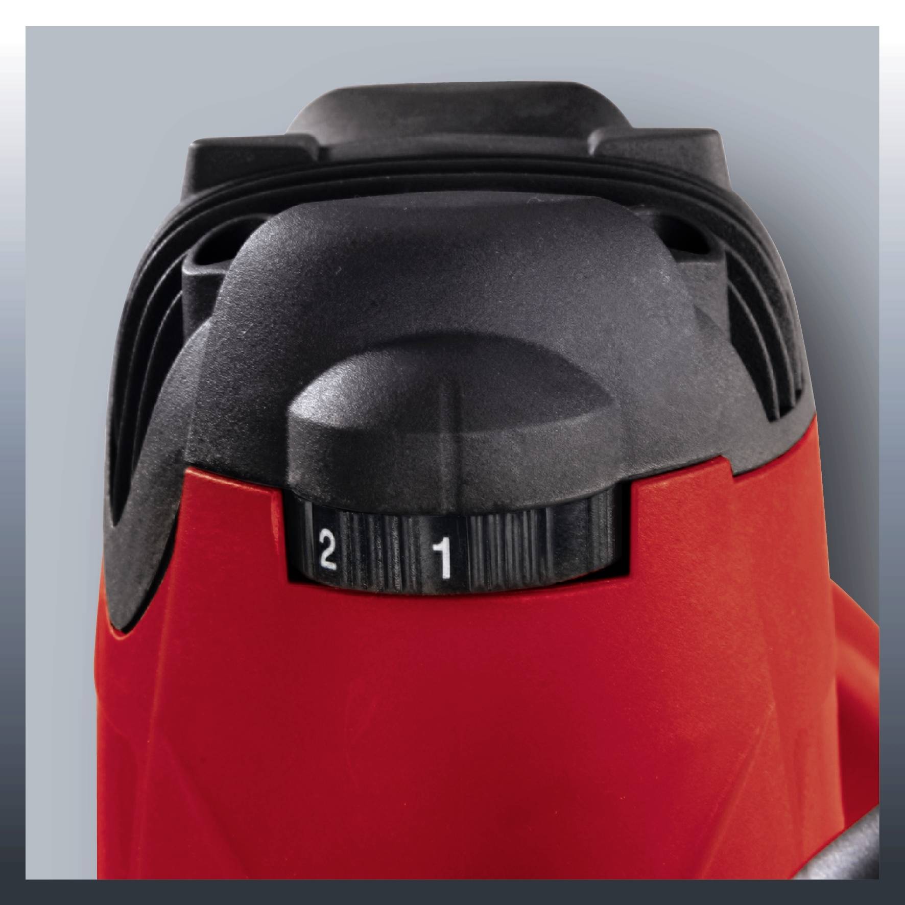 Egy fekete műanyag alkatrész, amely 1-től 2-ig terjedő skálával rendelkezik, egy piros eszközön van rögzítve, valószínűleg egy beállítási lehetőséget jelez.