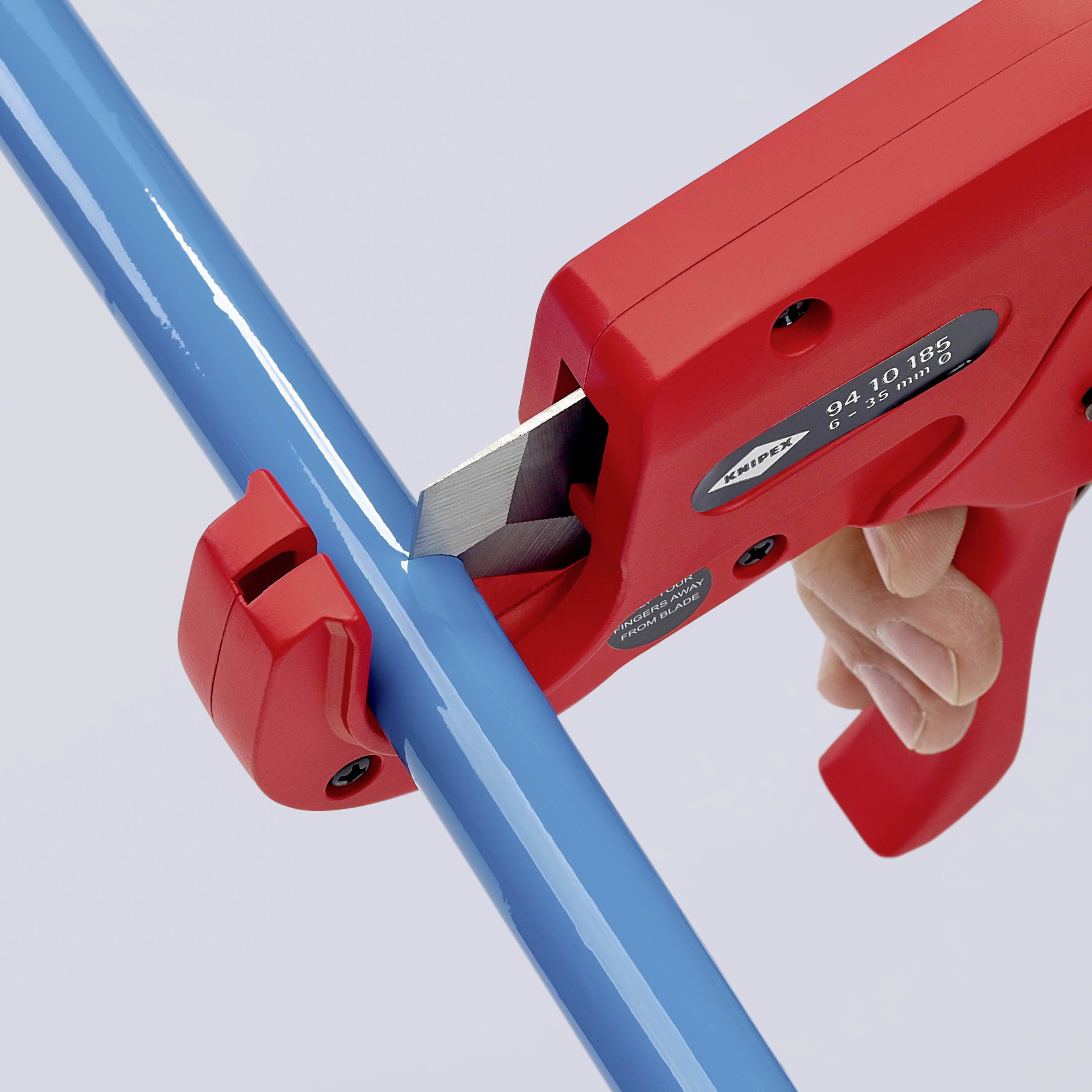 Egy személy egy piros csőollóval egy kék műanyagcsövet vág. A csőolló ergonomikus fogantyúval rendelkezik.