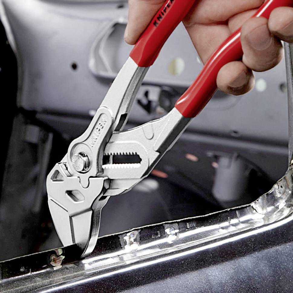 Egy kéz egy állítható fogót tart egy fémdarab ellen, valószínűleg ipari vagy kézműves környezetben.