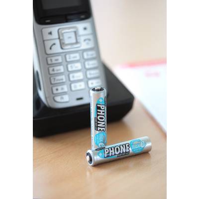 Két „PHONE max e" feliratú akkumulátor fekszik egy zsinór nélküli telefon előtt.