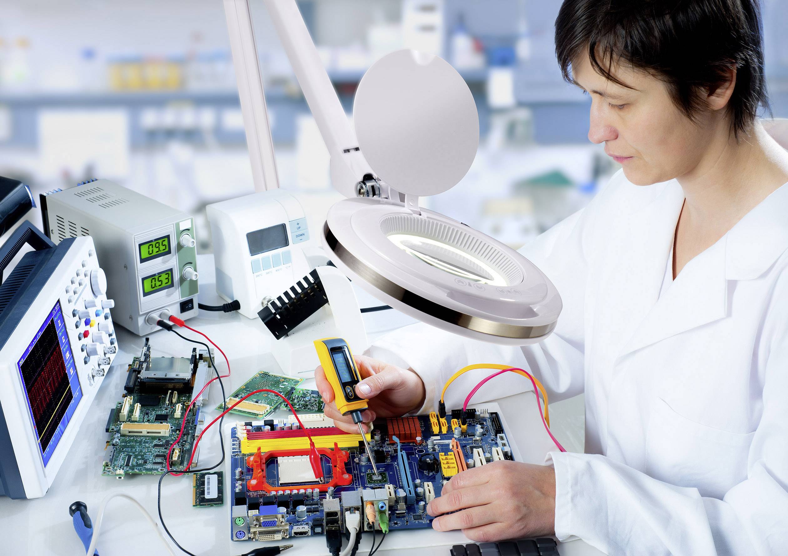 Egy személy egy laboratóriumban elektronikai alkatrészeken dolgozik egy nyomtatott áramkörön, körülvéve mérőeszközökkel és egy nagyítóval.