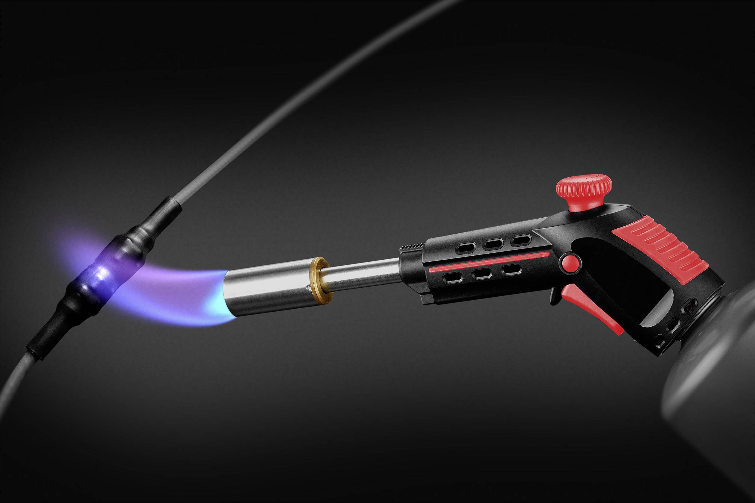 Egy kék lánggal égő gázégő egy fekete kábelt melegít egy sötét környezetben, valószínűleg javítás vagy csatlakoztatás céljából.