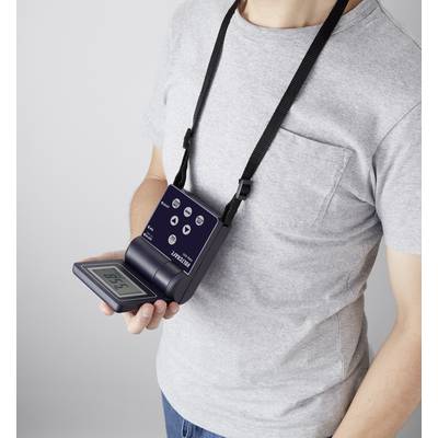 Egy személy szürke pólóban egy nyakba akasztható hordozható elektronikus eszközt tart, amelynek digitális kijelzője van.