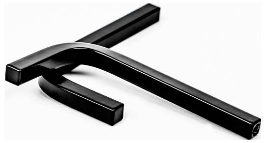 Két fekete fémrúd metszi egymást egy fehér felületen, minimálisan absztrakt kompozíciót alkotva.