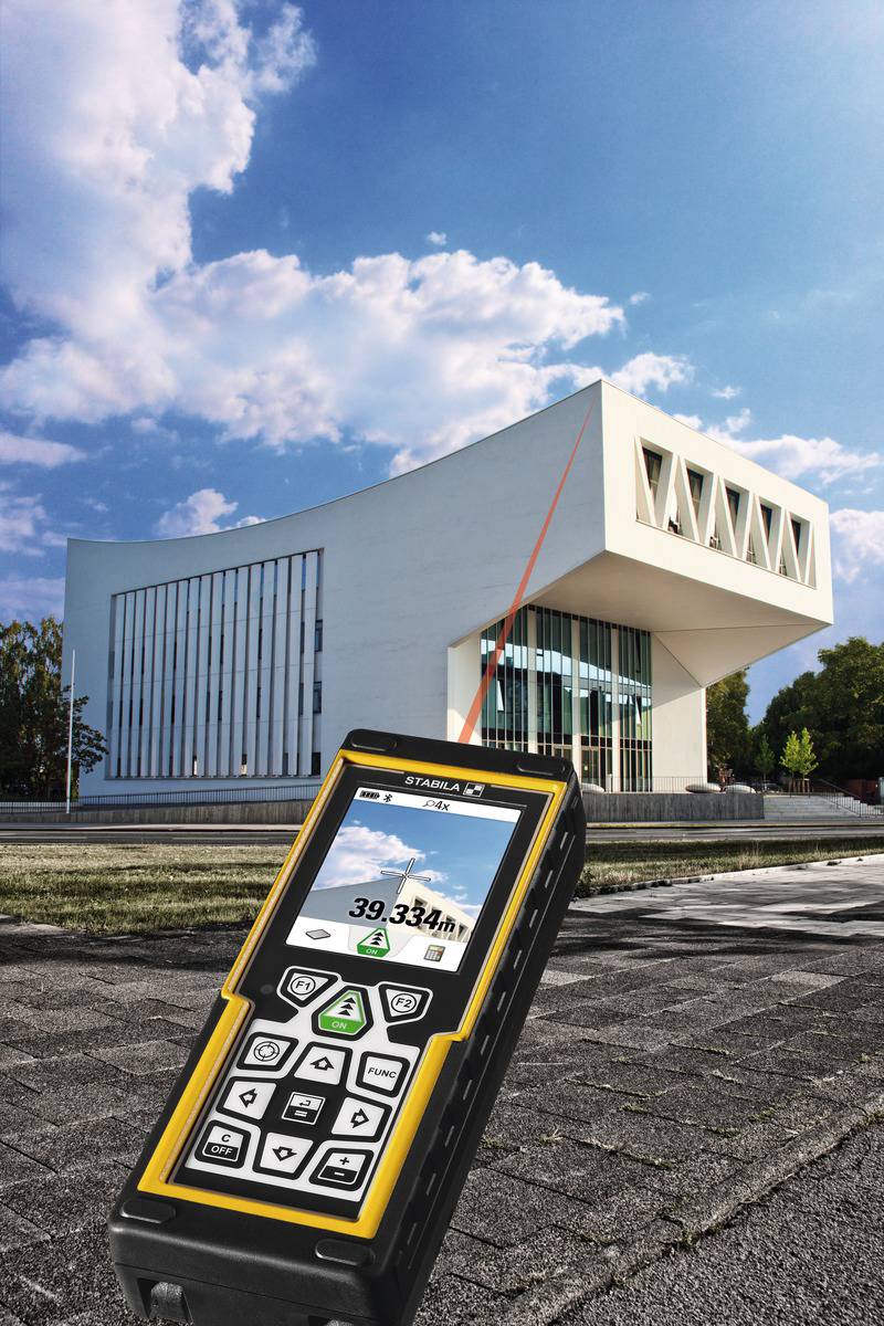 Egy távolságmérő lézerrel mutatja a távolságot egy modern, fehér épülethez, amelynek nagy ablakai vannak, és kék ég látható a háttérben.