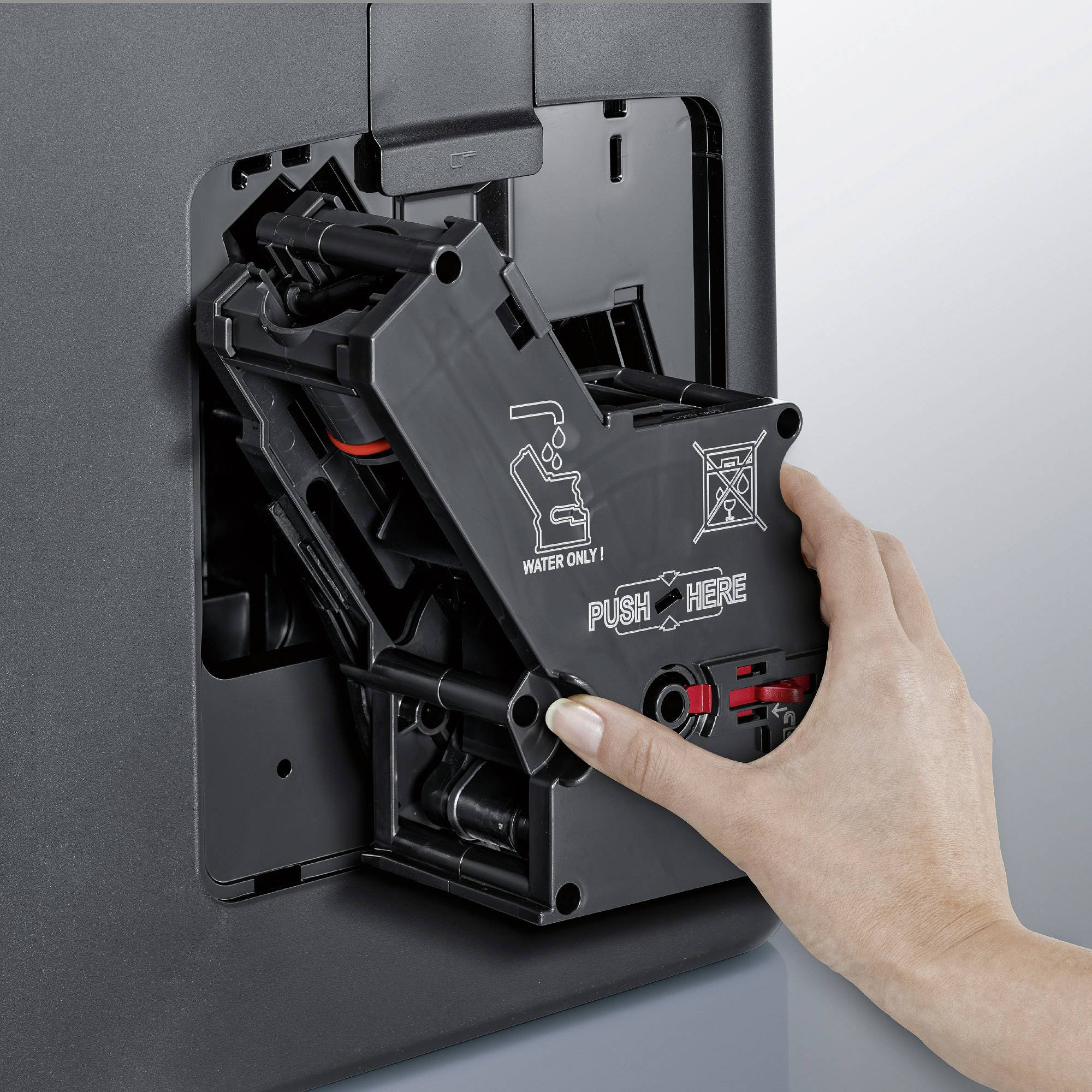 Egy kéz megnyomja egy kávéfőző automata mechanizmusát, hogy kinyissa a víztartályt. Egyértelmű útmutató látható, amelyen az 'ONLY WATER' felirat olvasható.