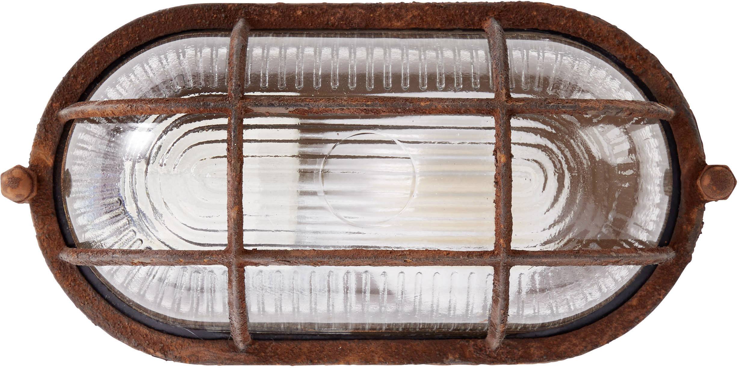 Rozsdás keretű fémrács vesz körül egy ovális üveglámpát.