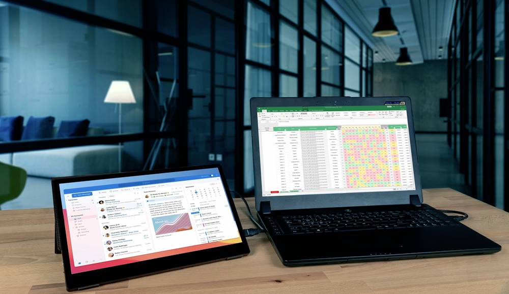 Két laptop egy modern irodai asztalon. A bal oldali képernyőn egy e-mail alkalmazás látható, a jobb oldalin egy színes táblázatkezelő.