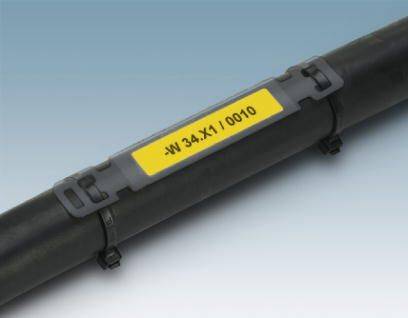 Egy fekete cső sárga címkével, amelyen a '-W 34.X1/0010' felirat szerepel. A címke egy szürke tartóban van rögzítve.