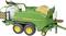 Zöld John Deere bálázógép sárga bálával, két kerékpárral, egy területen parkolva.