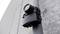 Egy fekete térfigyelő kamera van felszerelve egy fémoszlopra, és egy háztömb falára irányul.