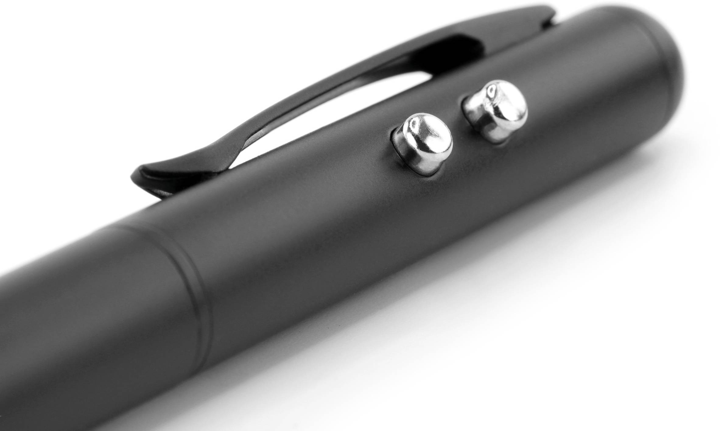 Fekete toll két ezüst gombbal és egy csipesszel, fehér felületen fektetve.