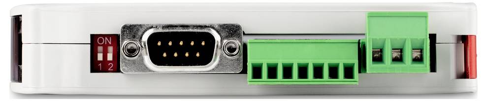 Közeli felvétel egy fehér elektronikai eszközről, amelynek különböző csatlakozóportjai vannak, köztük egy RS-232 csatlakozó és zöld kapcsok.