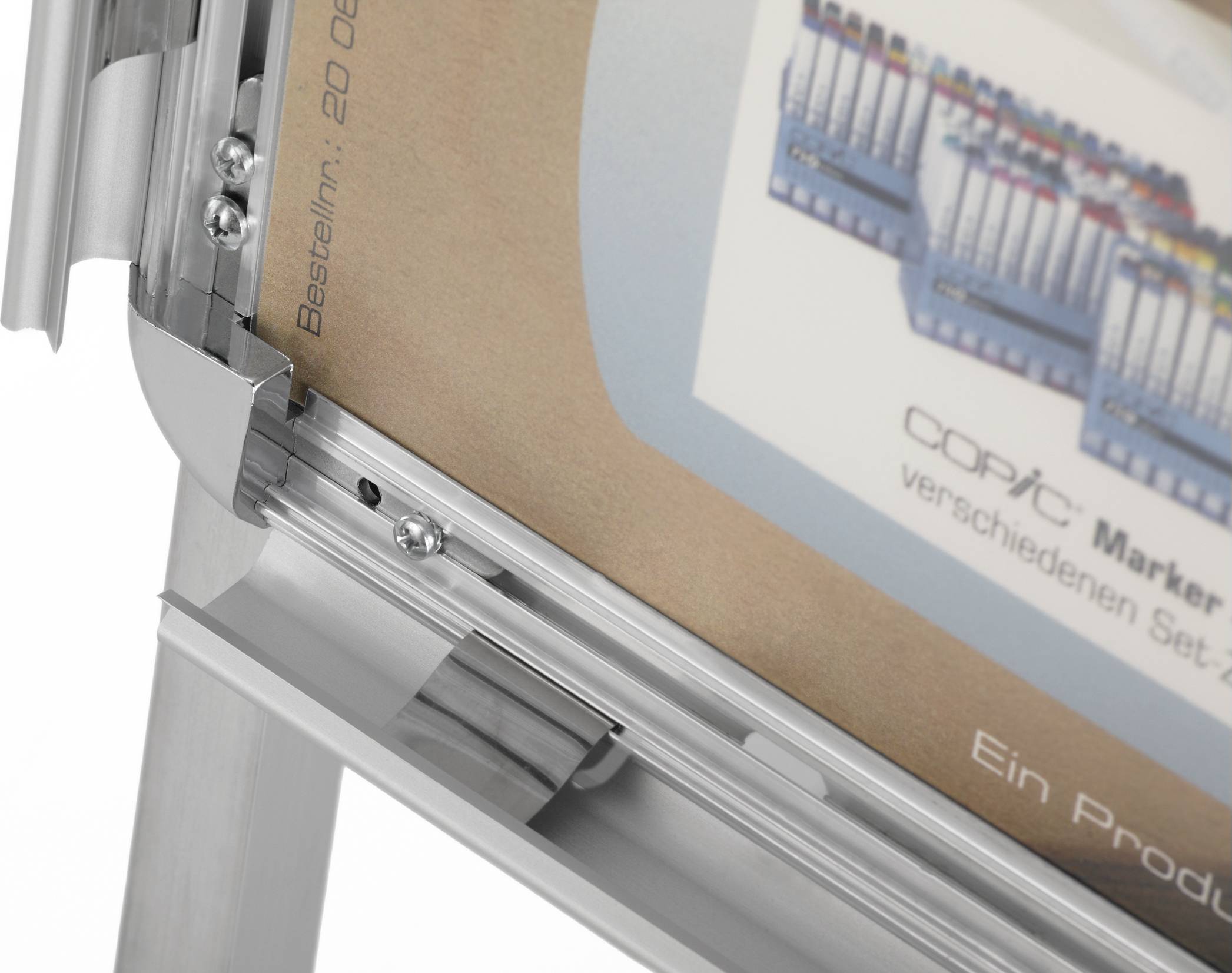 Egy ezüst állványon elhelyezett plakát 'Copic Marker' feliratot mutat, több marker-készlettel, a '20 065' rendelési számmal.