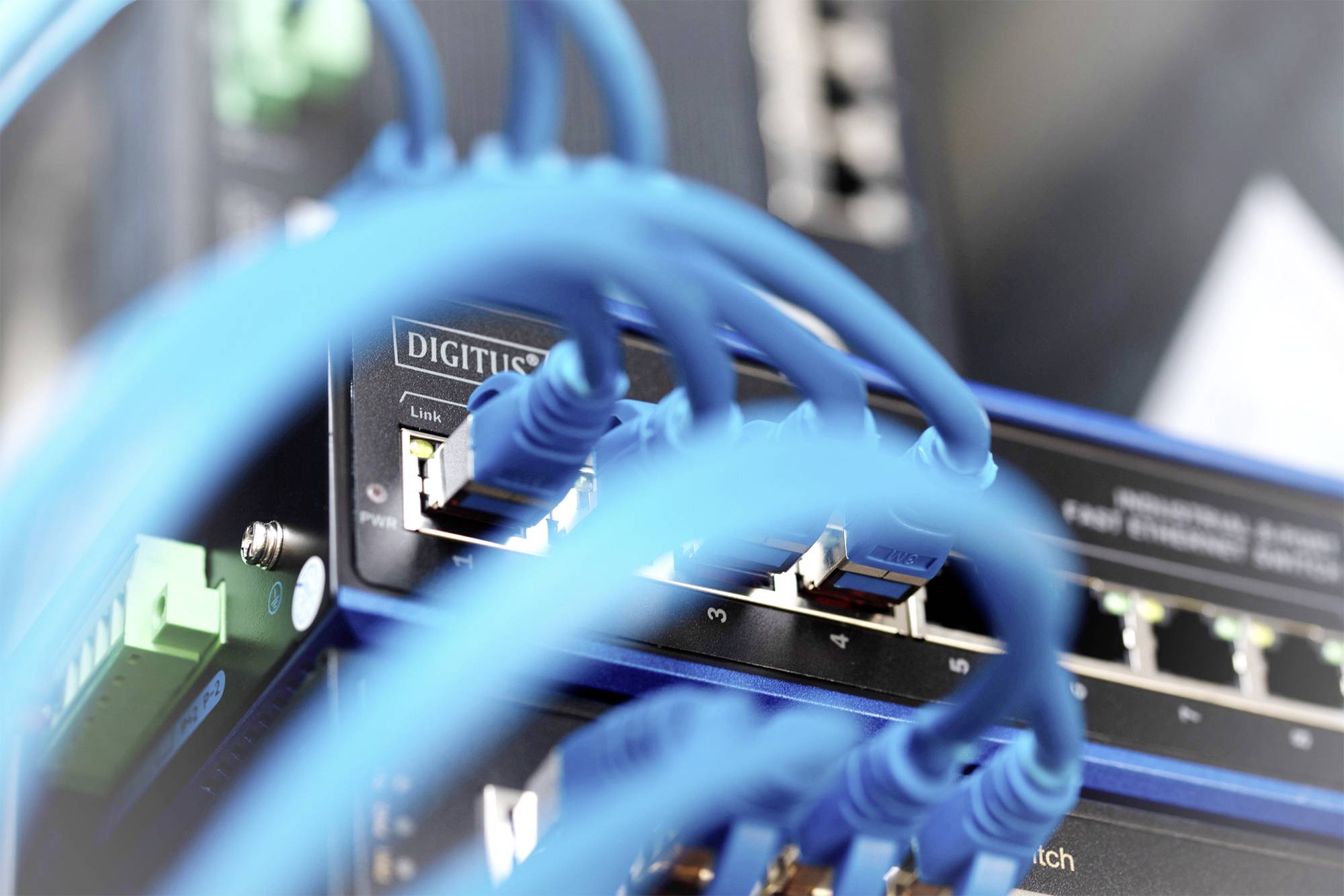 Egy hálózati switch több csatlakoztatott kék Ethernet-kábellel, amelyek kapcsolatot biztosítanak a hálózat különböző eszközei között.