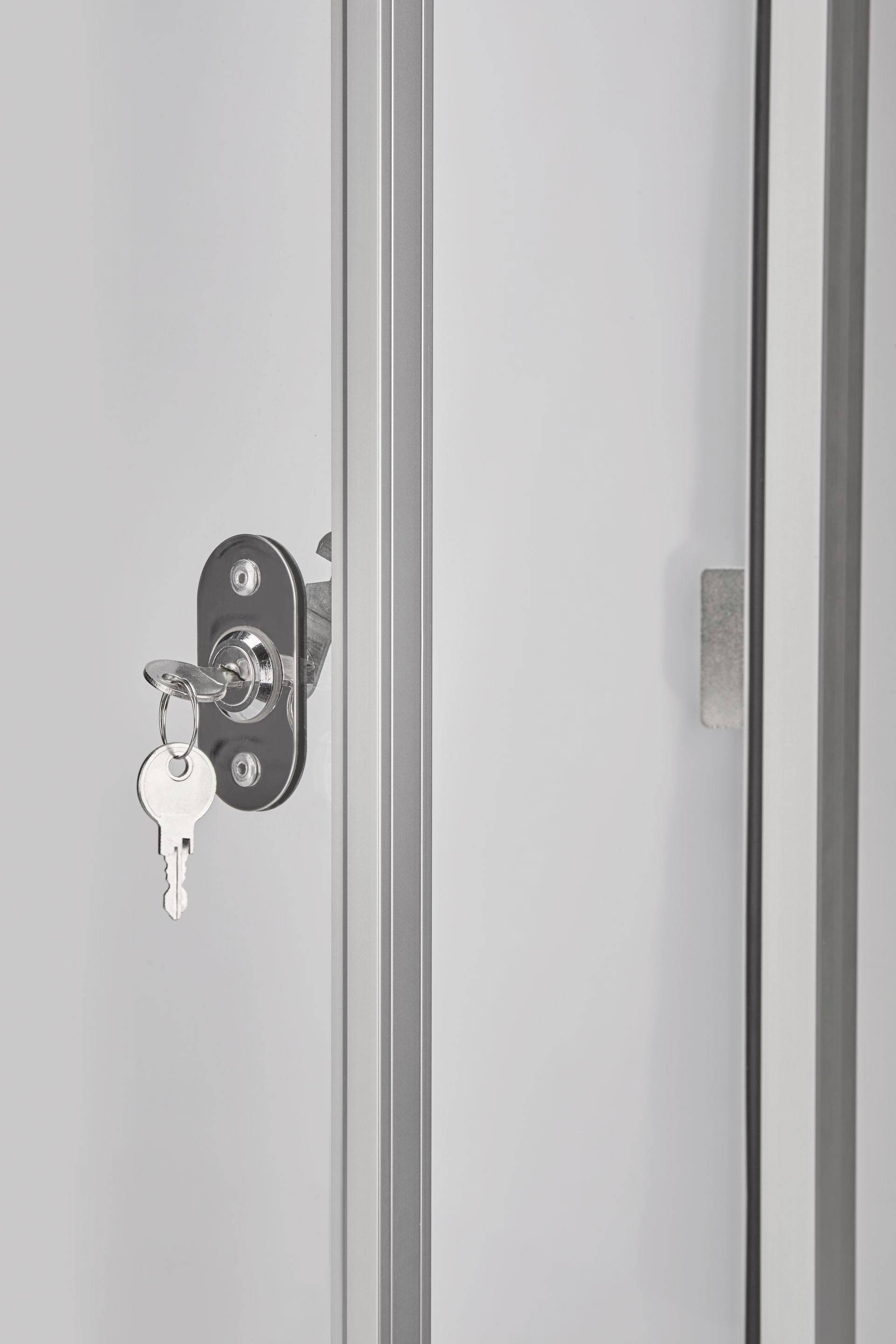 Egy kulcs lóg egy üvegajtó zárjában. A kulcson egy címke van. Az ajtó zárva van, és fémkerettel rendelkezik.