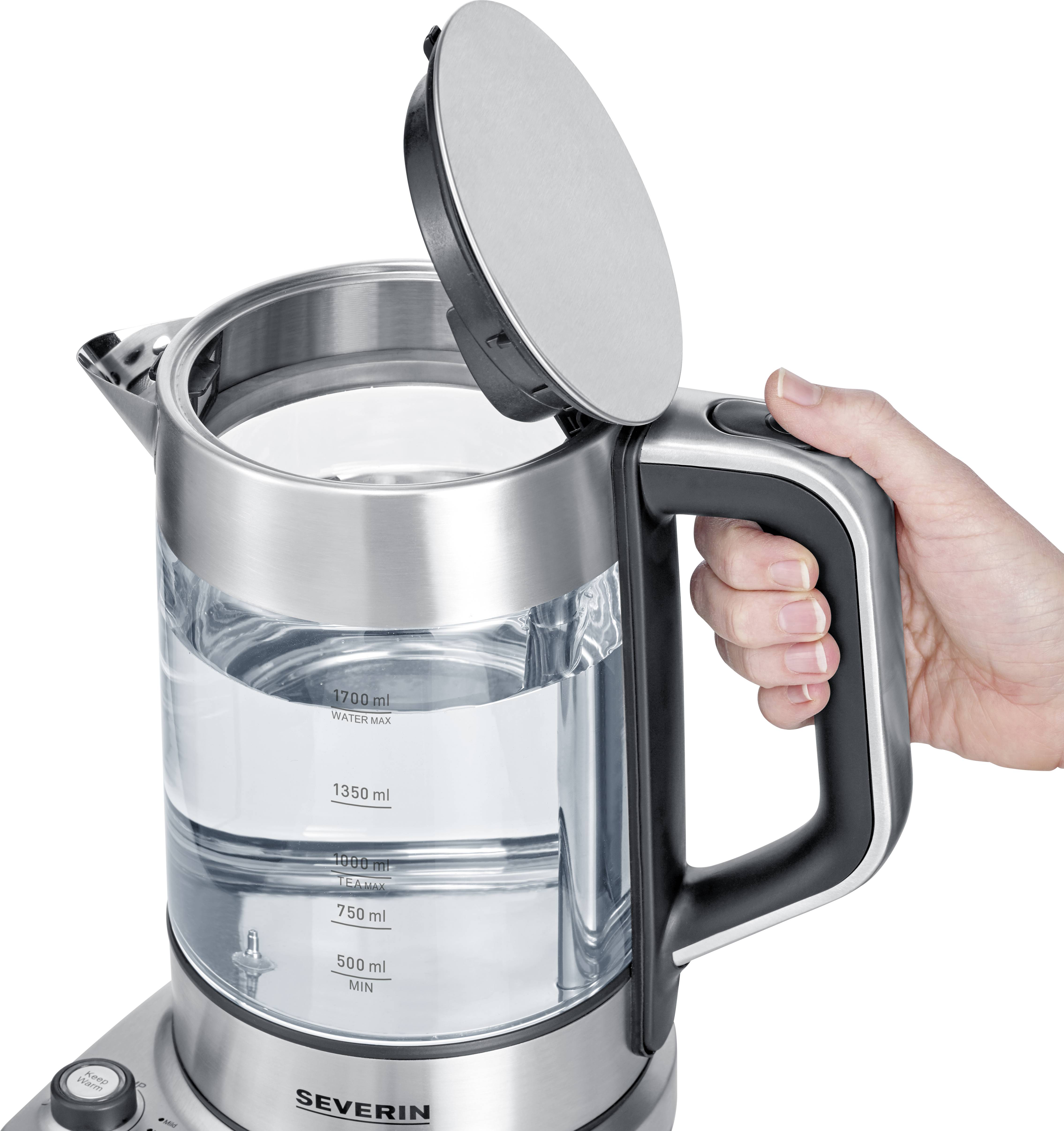 Egy kéz egy nyitott, ezüstös üveg vízforralót tart, amelyen vízszintjelző és milliliterben feltüntetett skála látható.