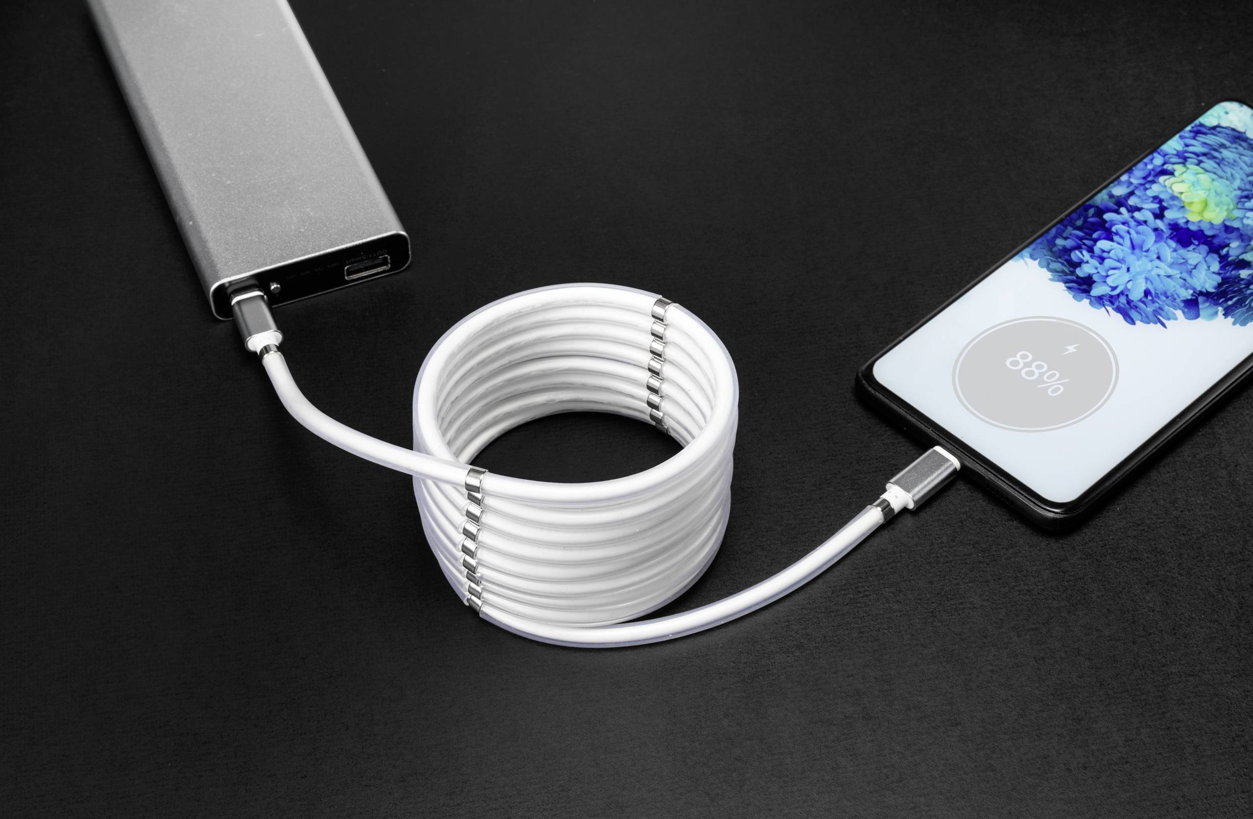 Egy mobiltelefon egy fehér kábellel töltődik egy powerbank segítségével. A telefon képernyőjén a töltöttségi szint '88%'-on látható.