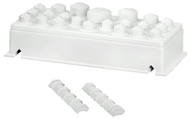 Egy fehér, téglalap alakú építőkocka, amelynek tetején levehető kis hengerek vannak. Mellette két kisebb darab fekszik.