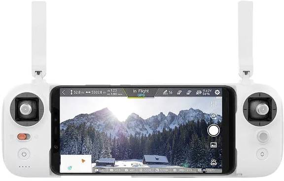 Egy távirányító berendezés beépített kijelzővel havas hegyeket és házakat mutató képet jelenít meg. A kijelzőn az 'In Flight' felirat látható.