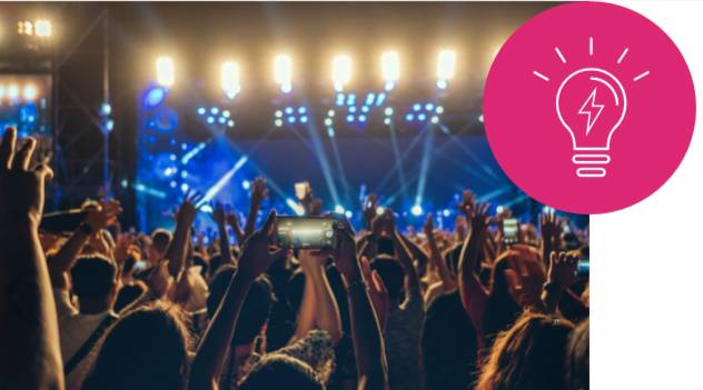 Tömeg emeli fel kezeit egy koncerten, kivilágított színpaddal. Jobb felső sarokban egy égő szimbóluma, amely egy ötletre utal.