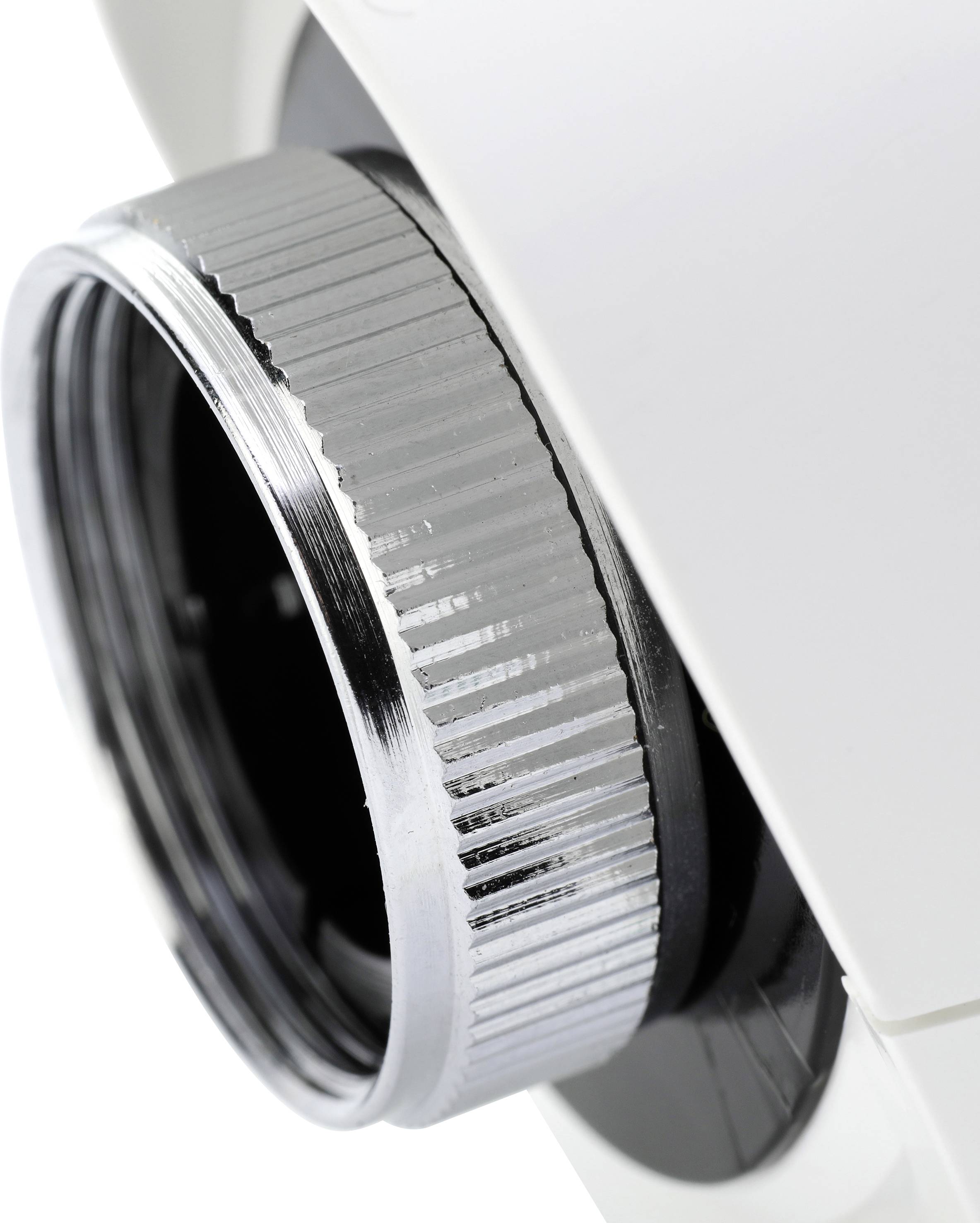 Közeli felvétel egy fehér eszköz ezüstös fém menetéről.