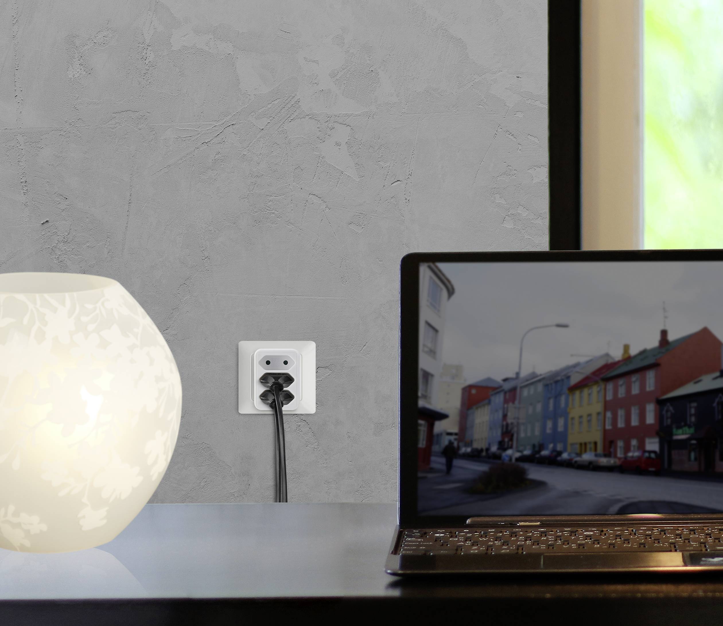 Egy laptop áll egy asztalon egy bekapcsolt lámpa mellett; a képernyőn egy színes utca képe látható.