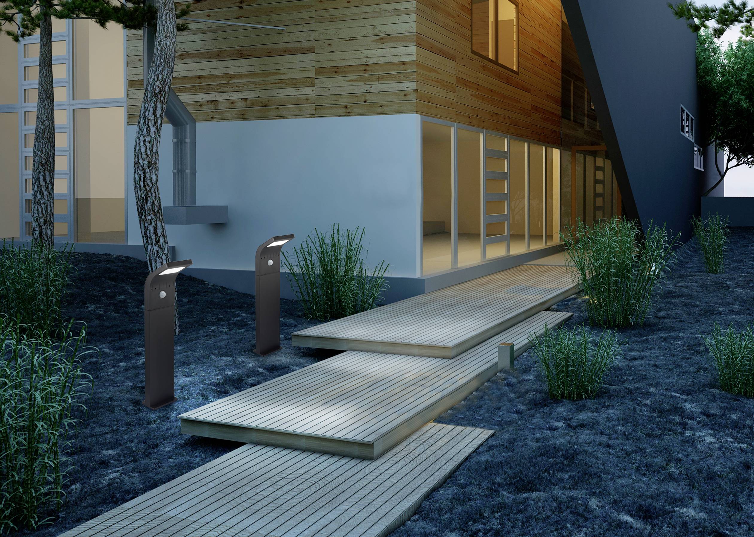 Faház nagy ablakokkal, növényektől körülvéve. Megvilágított faburkolatú út vezet a bejárathoz. Modern építészet esti fényben.