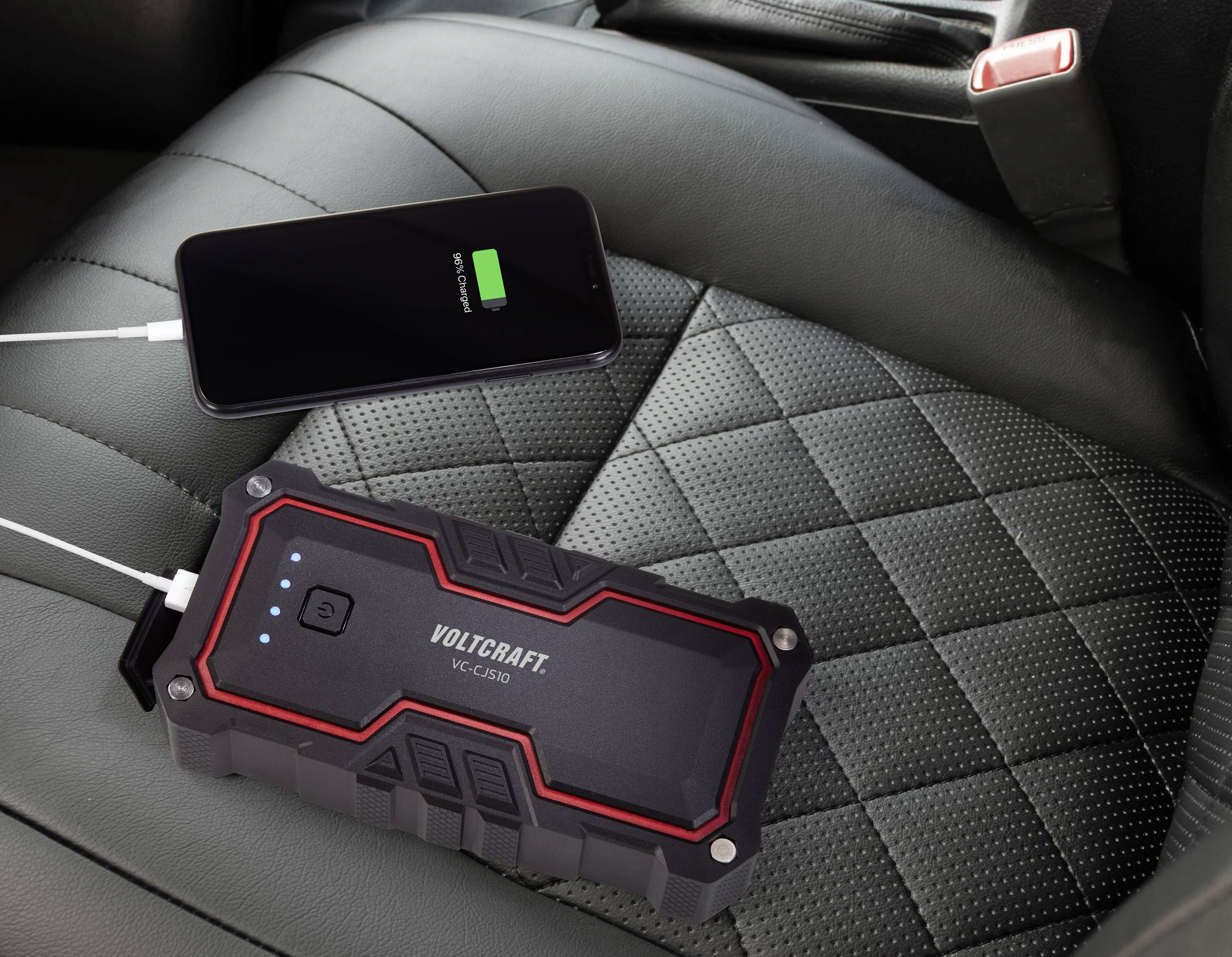 Egy powerbank egy autóülésén fekszik és tölt egy okostelefont. Az okostelefon kijelzője mutatja a töltés folyamatát.