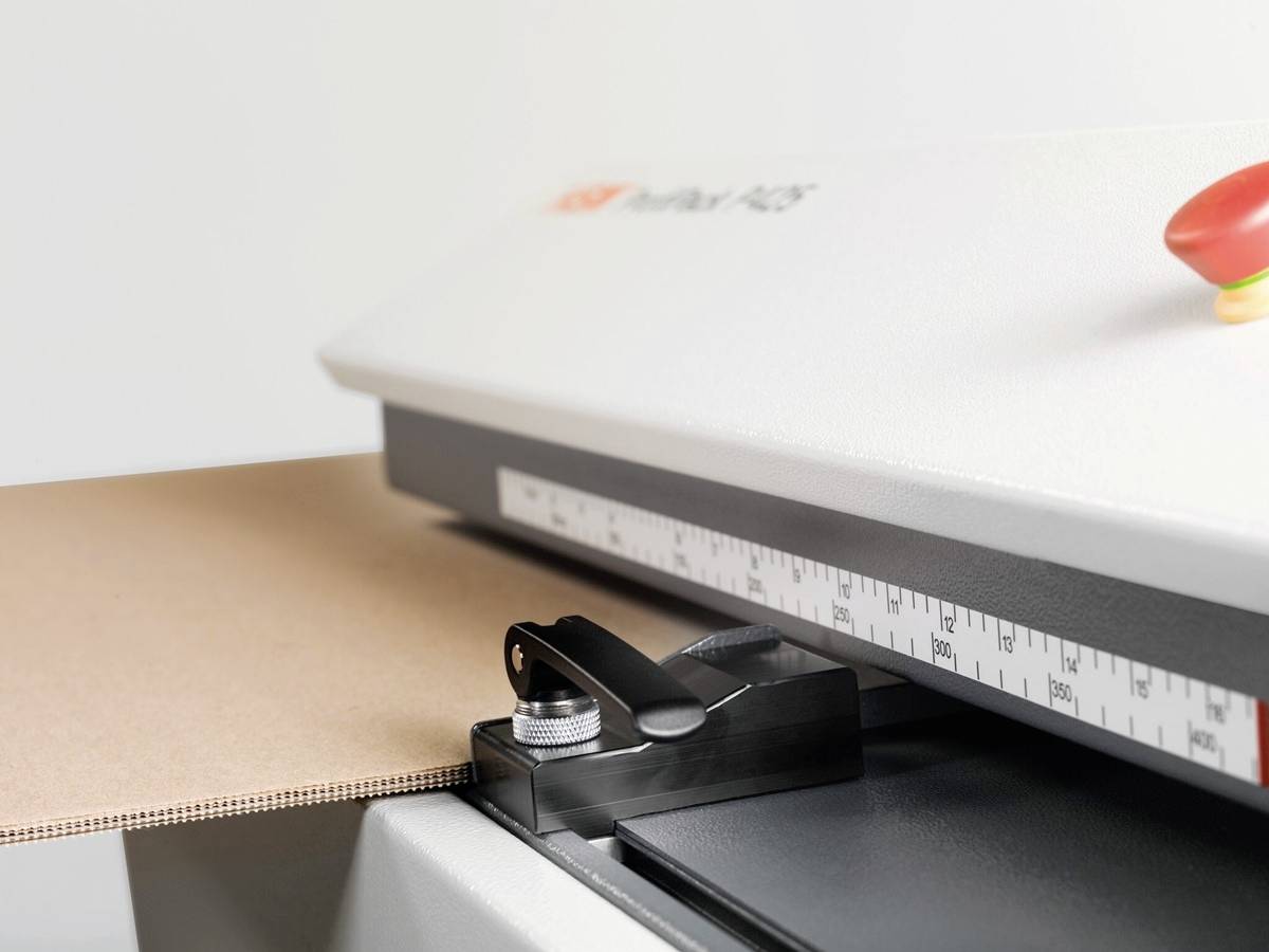 Egy papírvágó gép emelőkarral és mértékskálával a felületén, kartonlapok pontos vágásához.