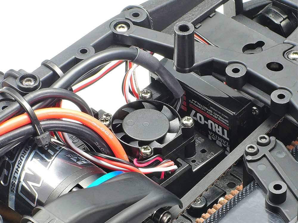 Egy RC-autó váza motorral, szervóegységgel és ventilátorral. Különböző kábelek kötik össze az alkatrészeket.