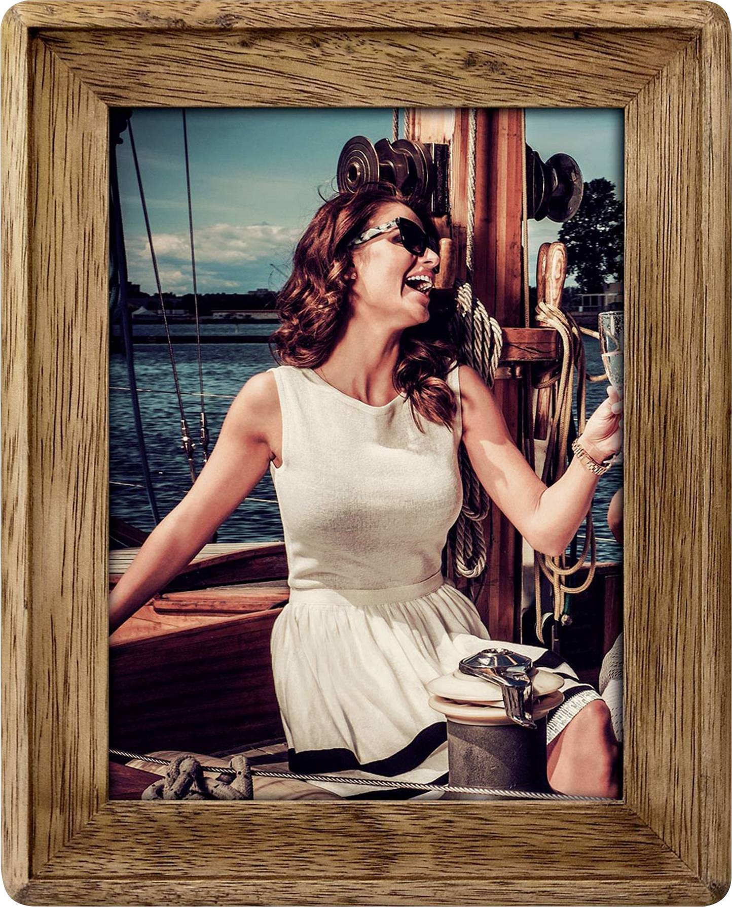 Egy fehér ruhás nő vidáman ül egy hajón, pezsgőspoharat tart a kezében. A háttérben víz és kék ég látható.