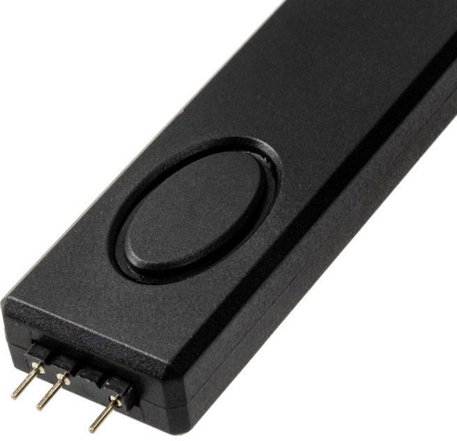 Egy fekete, téglalap alakú adapter, négy fémcsatlakozóval az egyik végén és egy ovális gombbal a tetején.