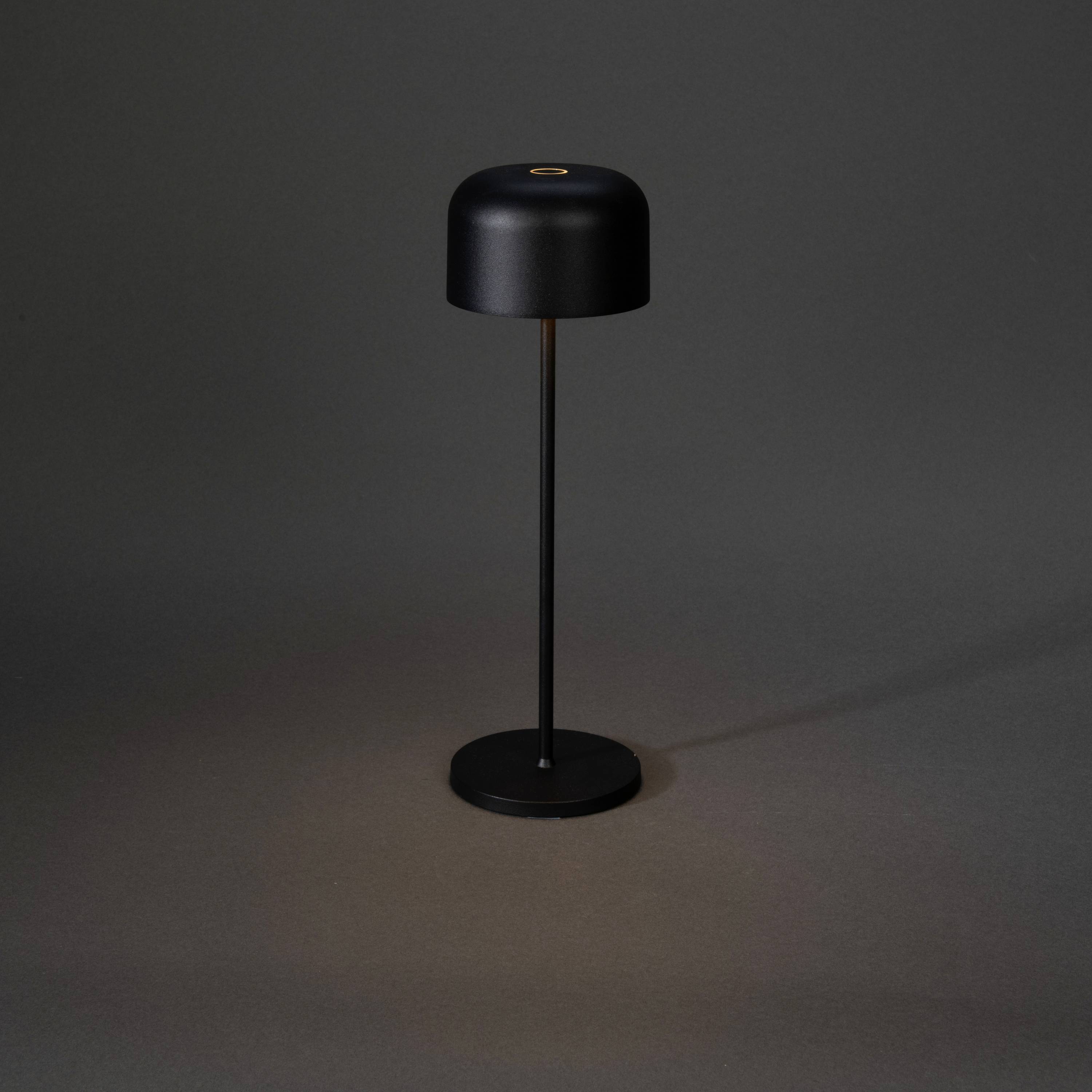 Egy egyszerű, fekete állólámpa kerek ernyővel szürke háttér előtt. Minimalista dizájn, modern enteriőrökhöz ideális.