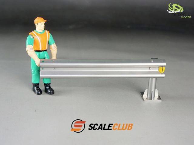 Egy munkásruhás játékfigura áll egy miniatűr védőkorlát mellett. A háttérben a 'SCALECLUB' logó látható.