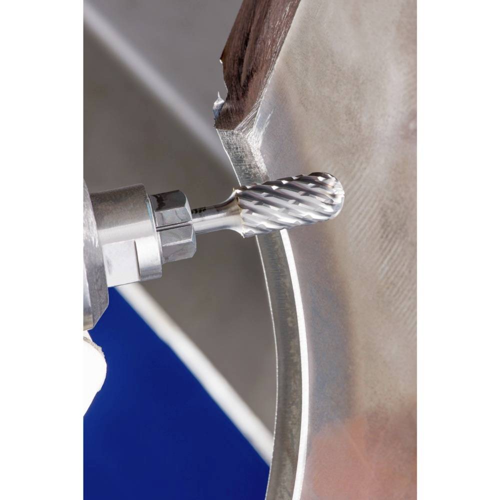 Egy fémdarab szélén dolgozó maró közelképe ipari gyártást vagy kézműves munkát mutat.