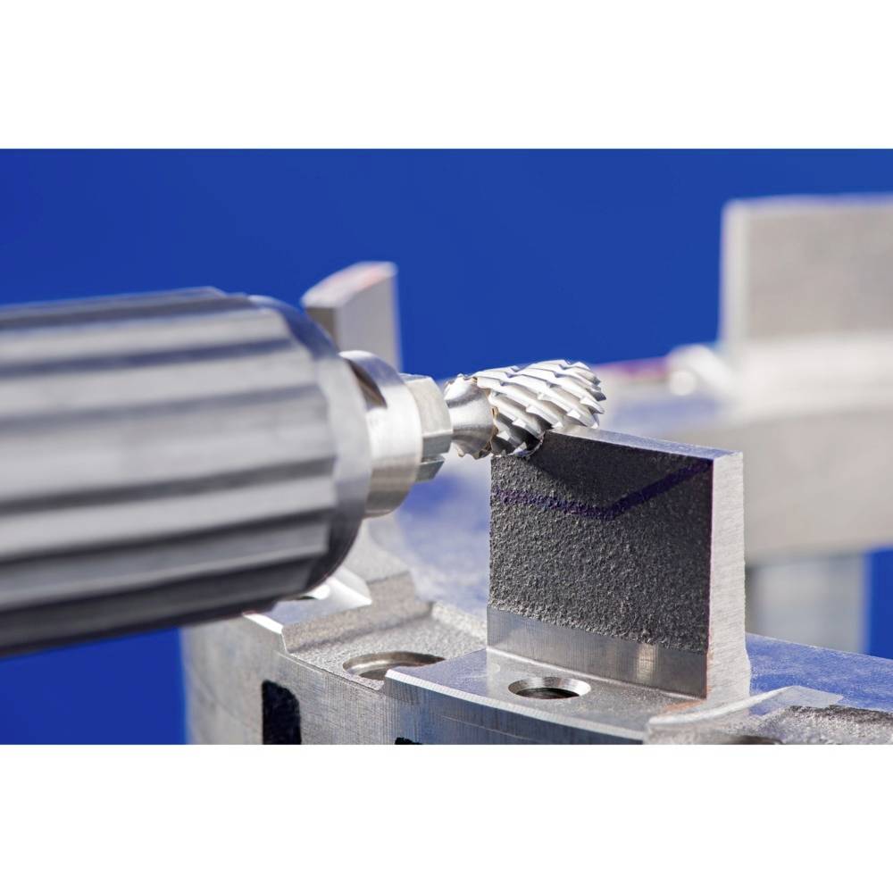 Egy elektromos csiszolóeszköz precízen megmunkálja egy fémtömb szélét egy olyan asztalon, amely egy műhely vagy termelési környezet része.